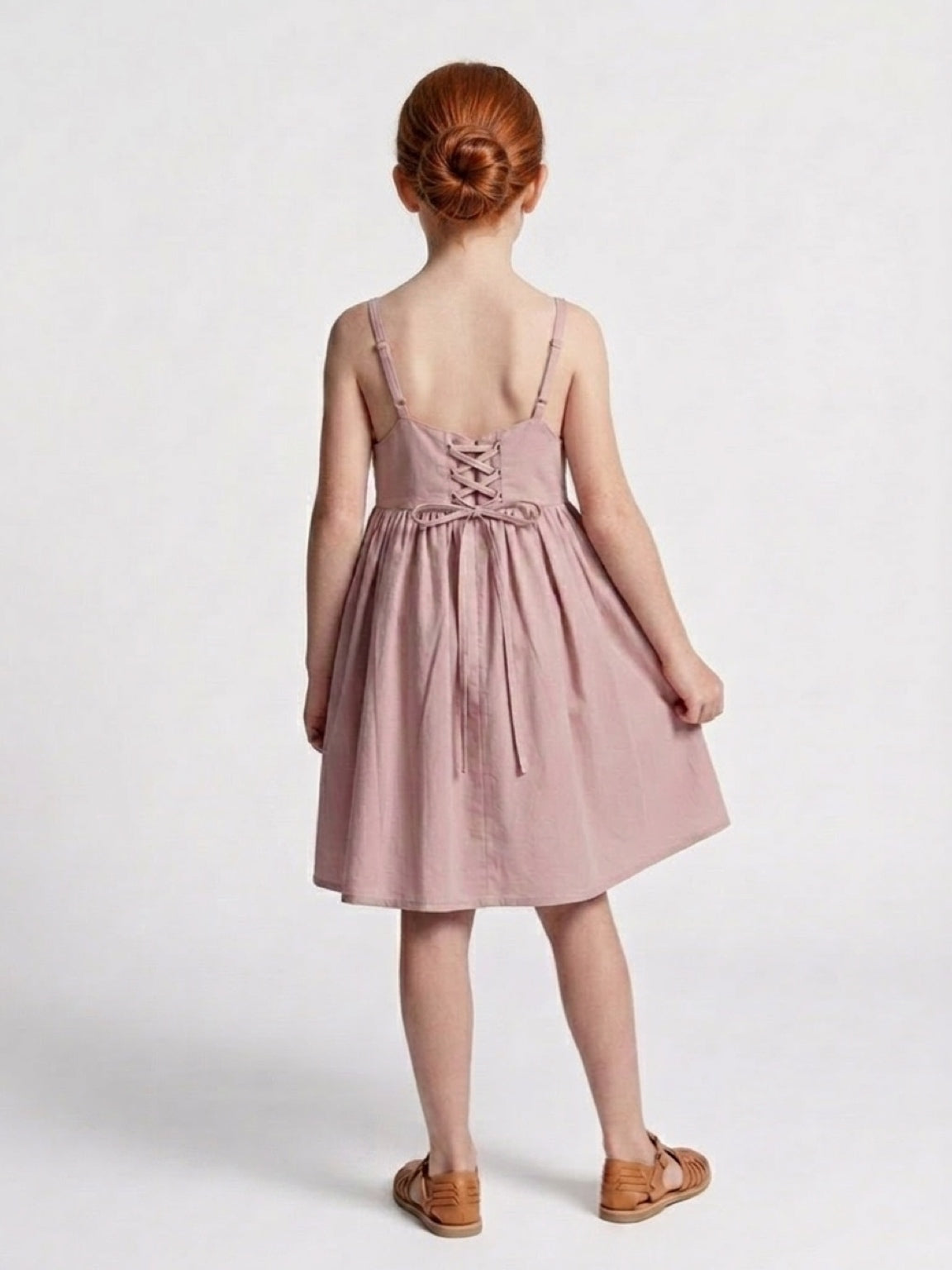 Young girl wearing a pink dress with a white background