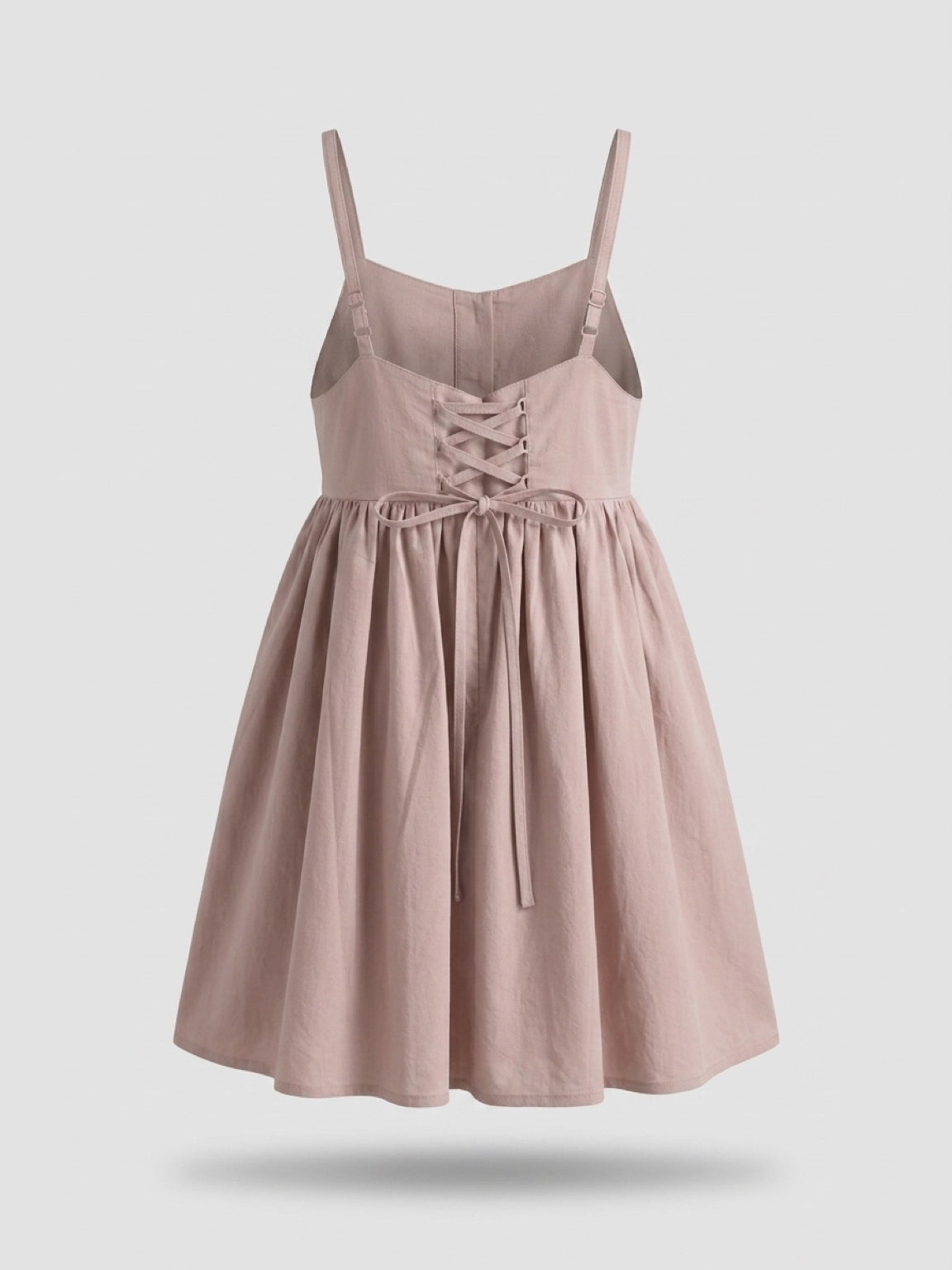 Pink dress with lace-up front and bow detail on a light gray background