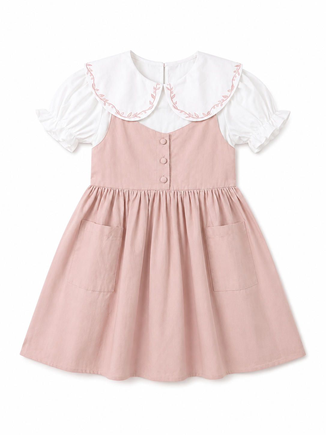 A toddler girl's dress featuring a dusty pink pinafore-style skirt with front pockets and a white short-sleeve top layered underneath, decorated with a large white Peter Pan collar trimmed in pink ruffle.