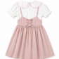 A pink pinafore-style dress with thin straps, a lace-up back, and a flared skirt, layered over a white short-sleeve blouse with a large ruffled collar.