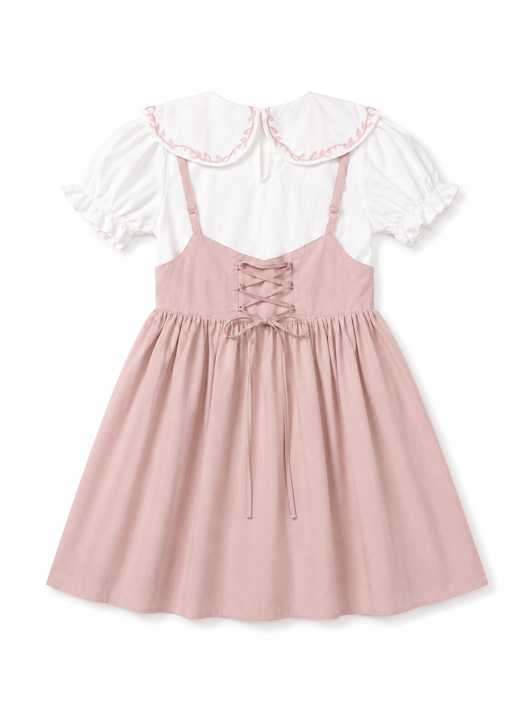 A pink pinafore-style dress with thin straps, a lace-up back, and a flared skirt, layered over a white short-sleeve blouse with a large ruffled collar.