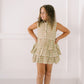 Young girl wearing a sleeveless dress with ruffled layers against a white background