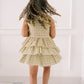 Child wearing a floral dress standing against a white wall
