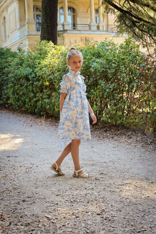 Young girl in a floral dress walking on a path with a classical building in the background