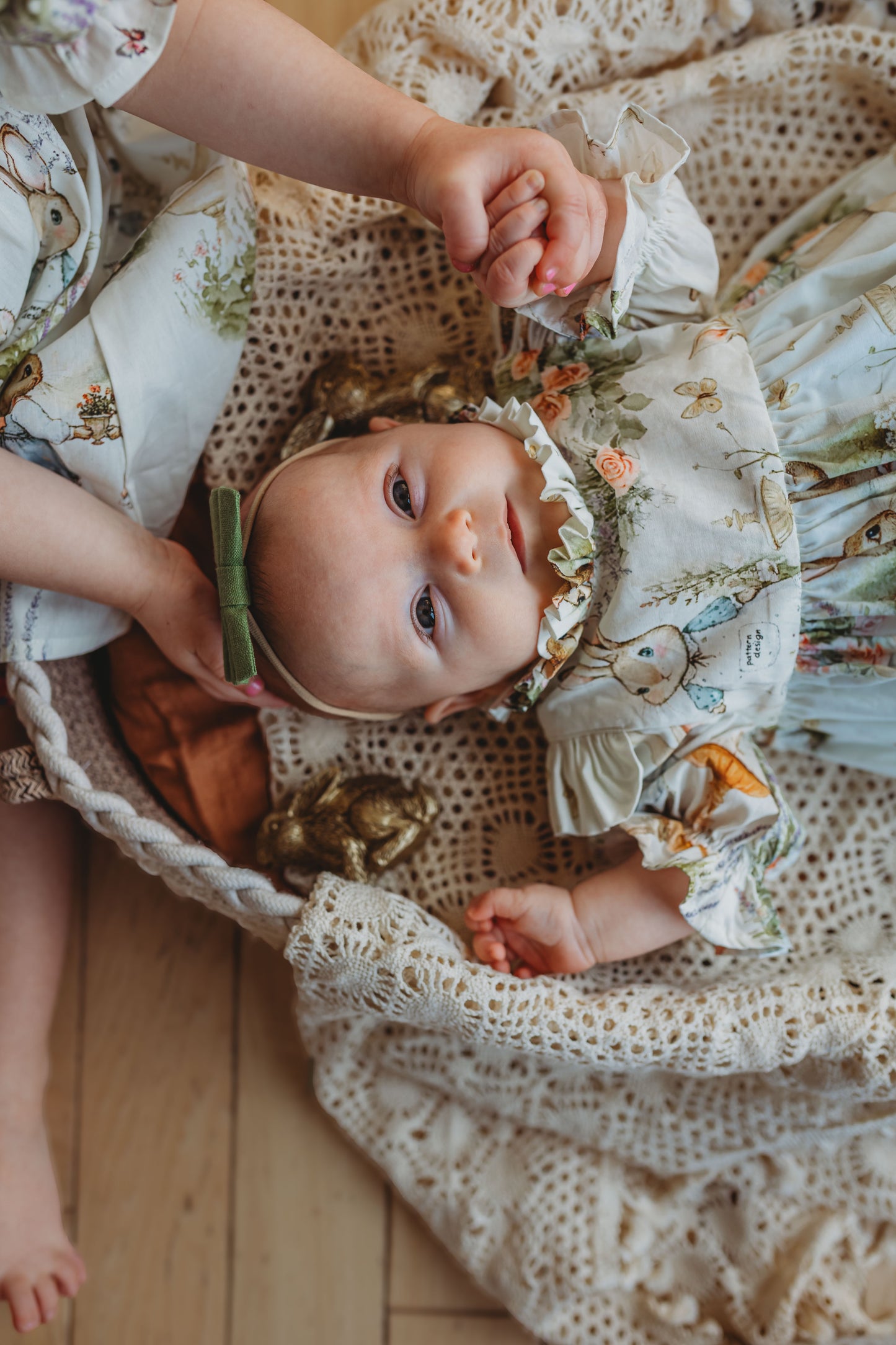 Baby in a floral outfit lying in a woven basket with a soft focus background