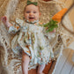 Baby in a floral dress lying in a wooden basket with a textured blanket