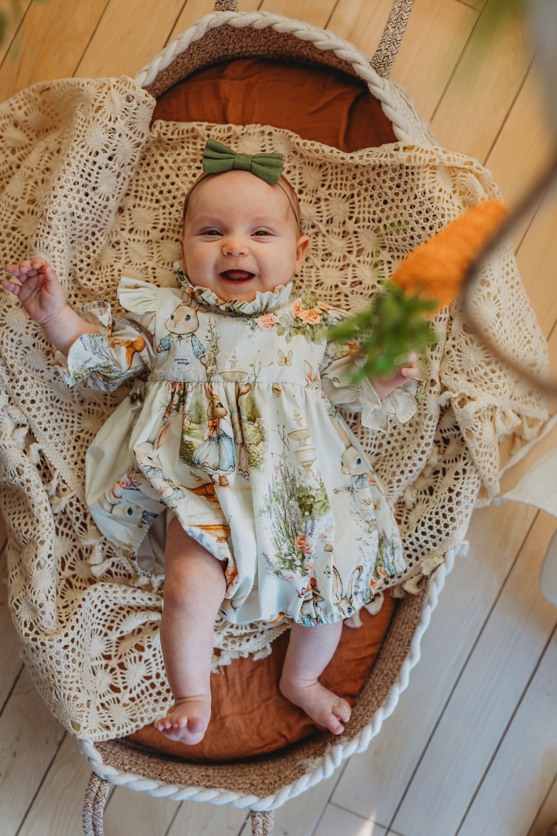 Baby in a floral dress lying in a wooden basket with a textured blanket