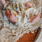 Baby wrapped in a floral blanket with bunny patterns, sitting on a textured surface.