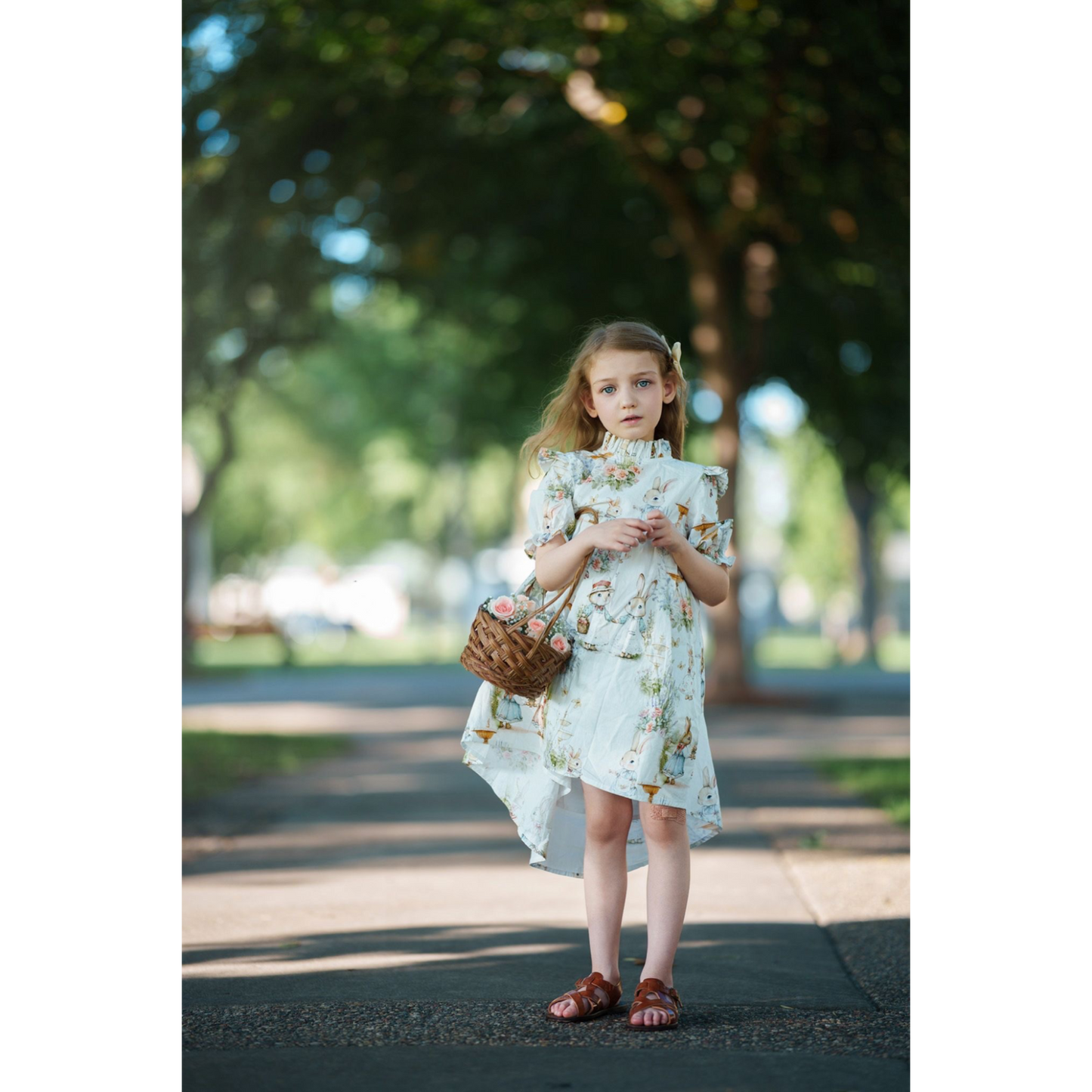 Young girl in a floral dress standing outdoors with trees in the background