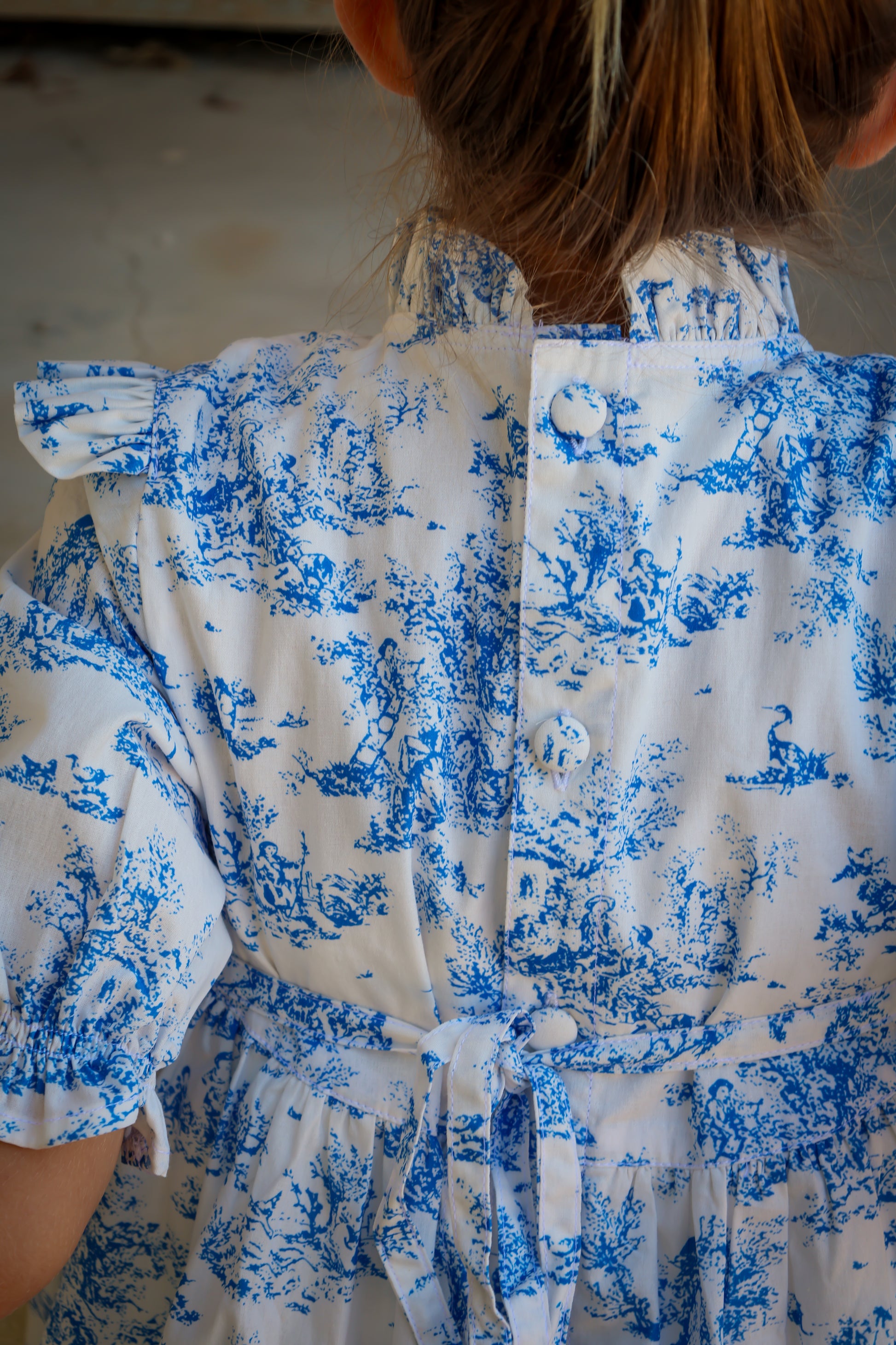 Person wearing a blue and white patterned shirt with a neutral background