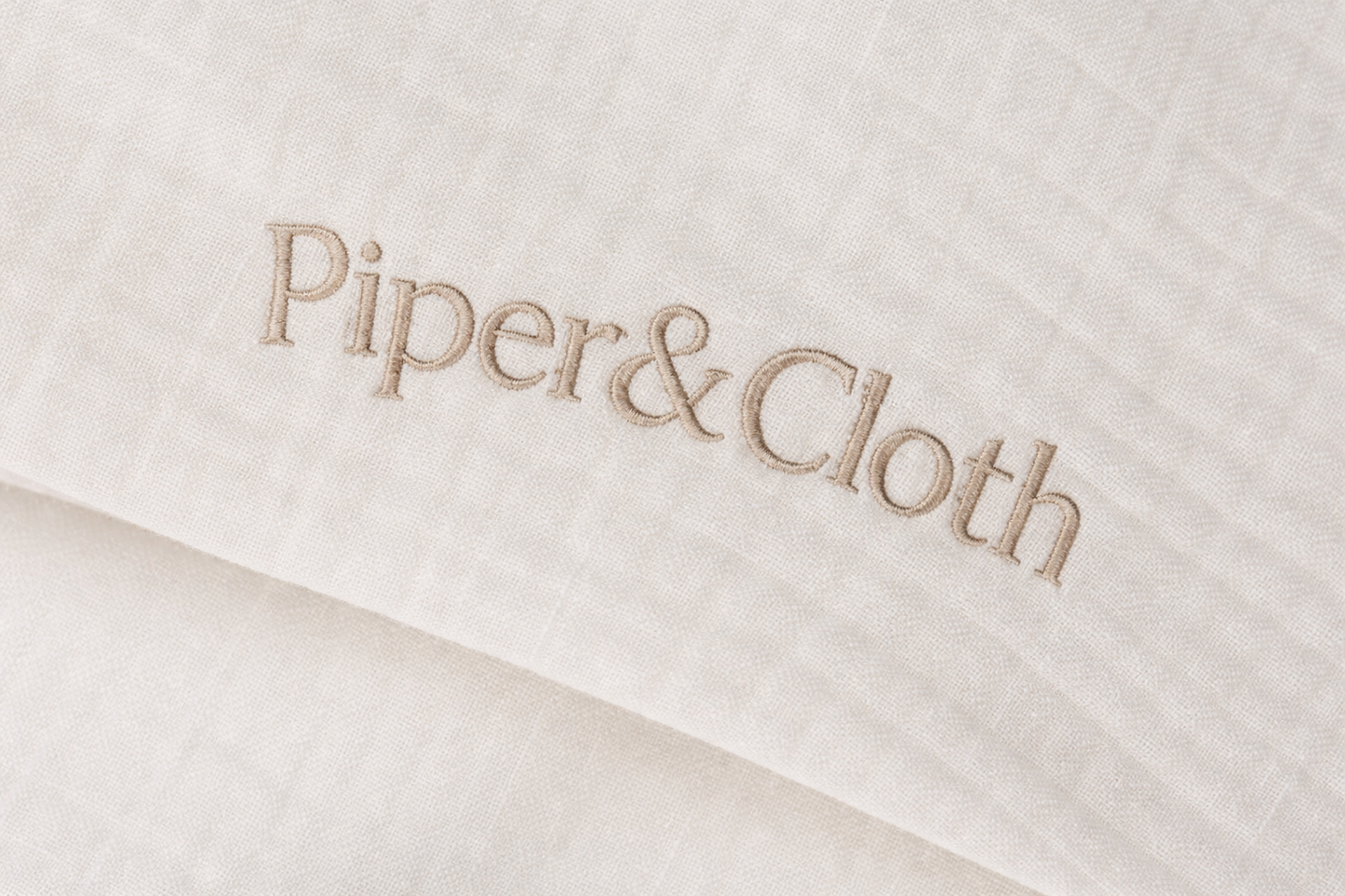 Close-up of 'Piper & Cloth' logo on a textured fabric background