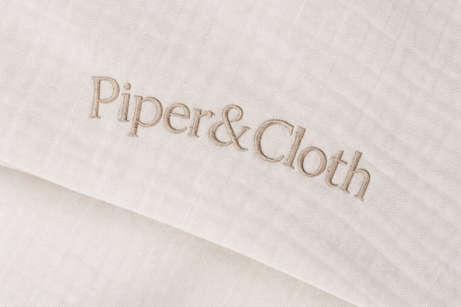 Close-up of 'Piper & Cloth' logo on a textured fabric background