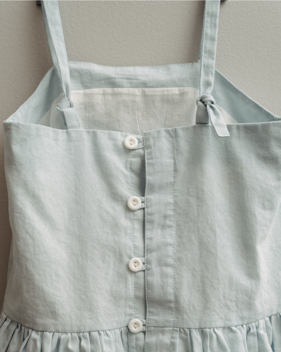 Light blue apron with buttons on a neutral background