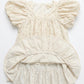 Beige baby romper with ruffled details on a white background