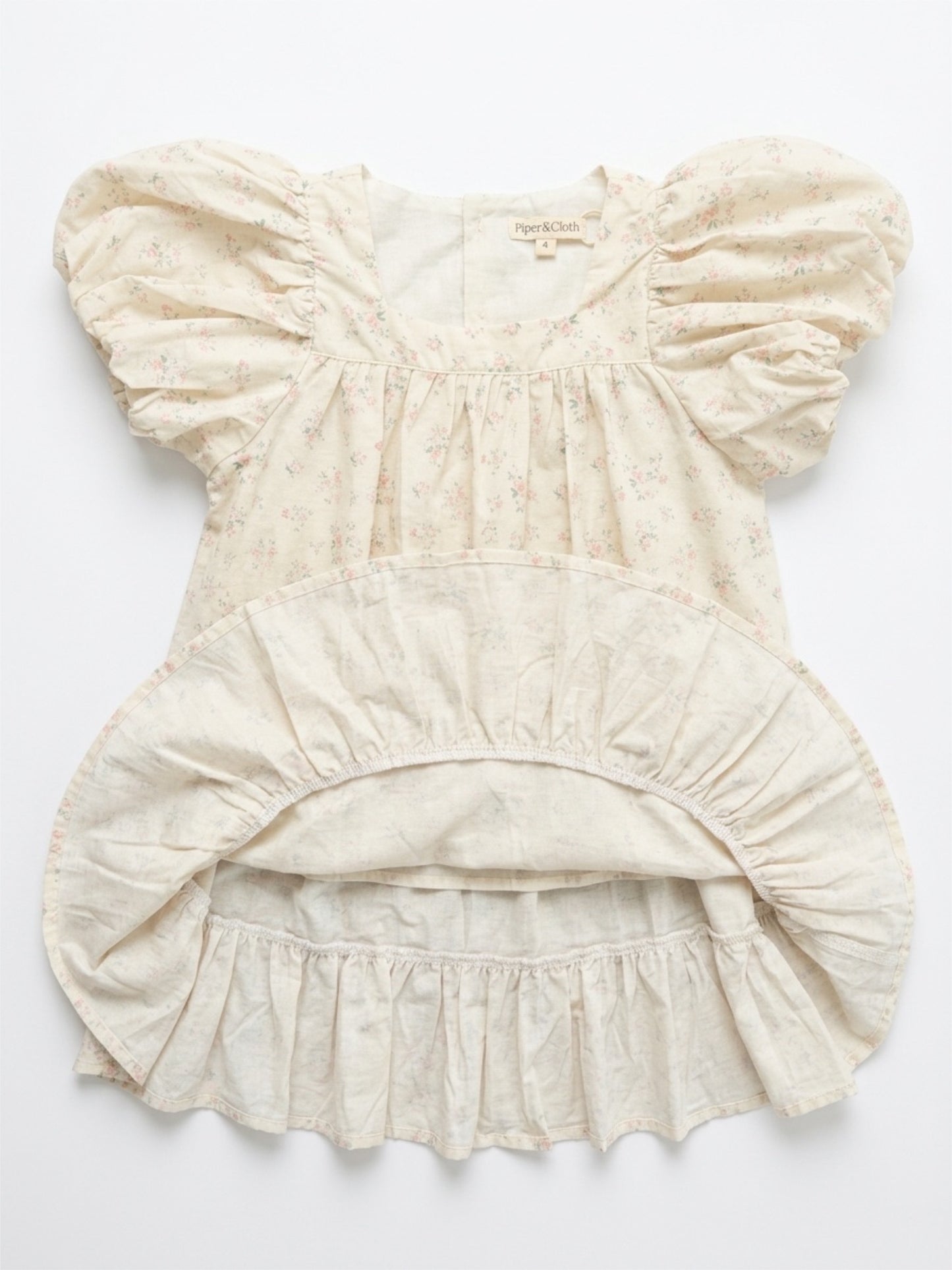 Beige baby romper with ruffled details on a white background