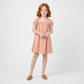 Young girl wearing a peach dress on a white background
