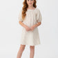 Young girl wearing a white dress with a subtle pattern on a white background