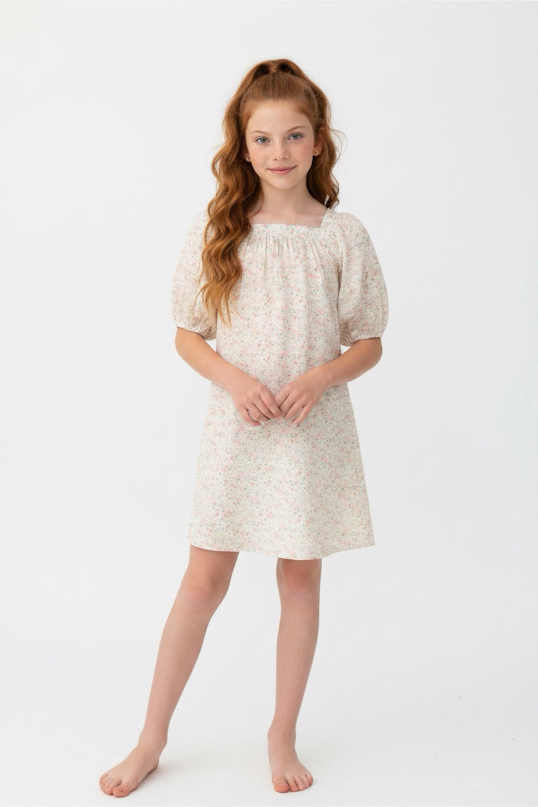 Young girl wearing a white dress with a subtle pattern on a white background