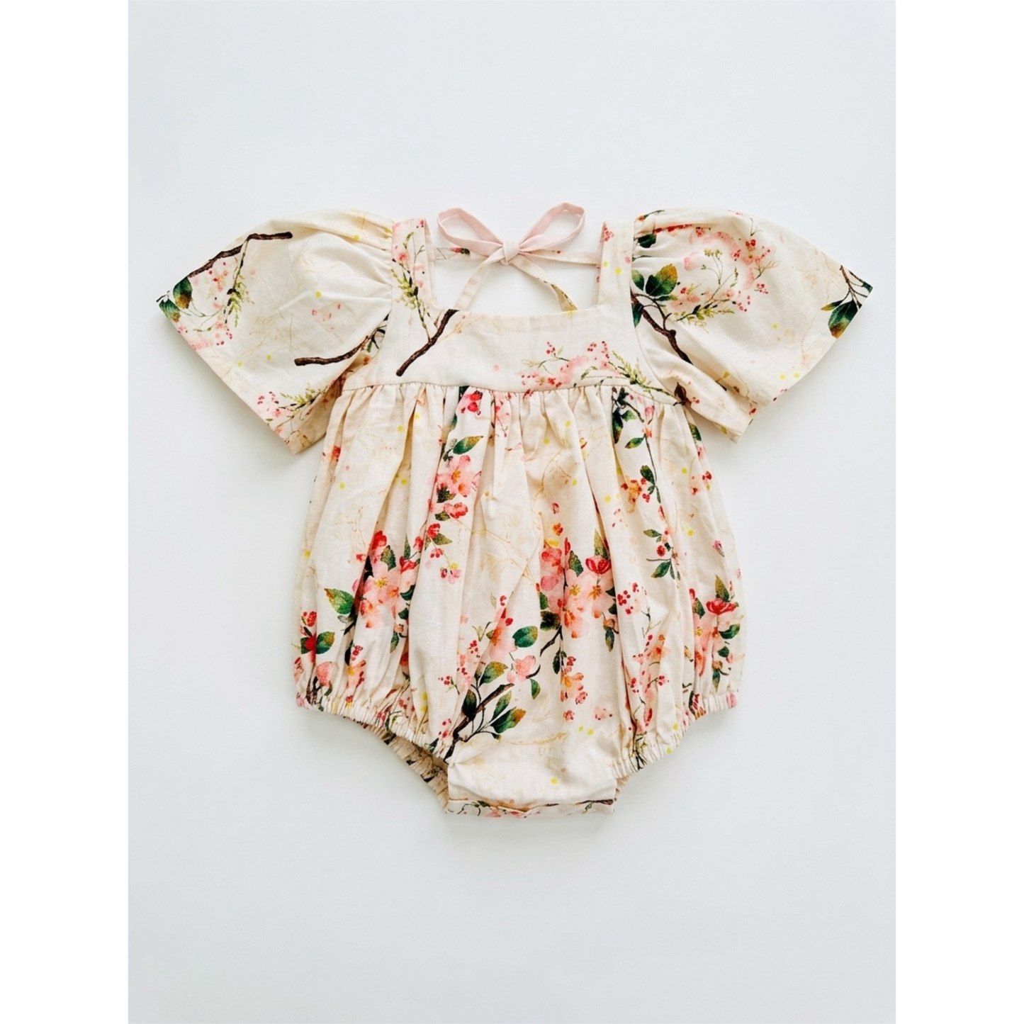 Floral baby romper with a bow on a light gray background