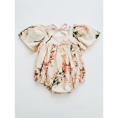 Floral baby romper with a bow on a light gray background