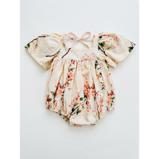 Floral baby romper with a bow on a light gray background
