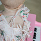 Baby in a floral Bubble  sitting on a pink piano