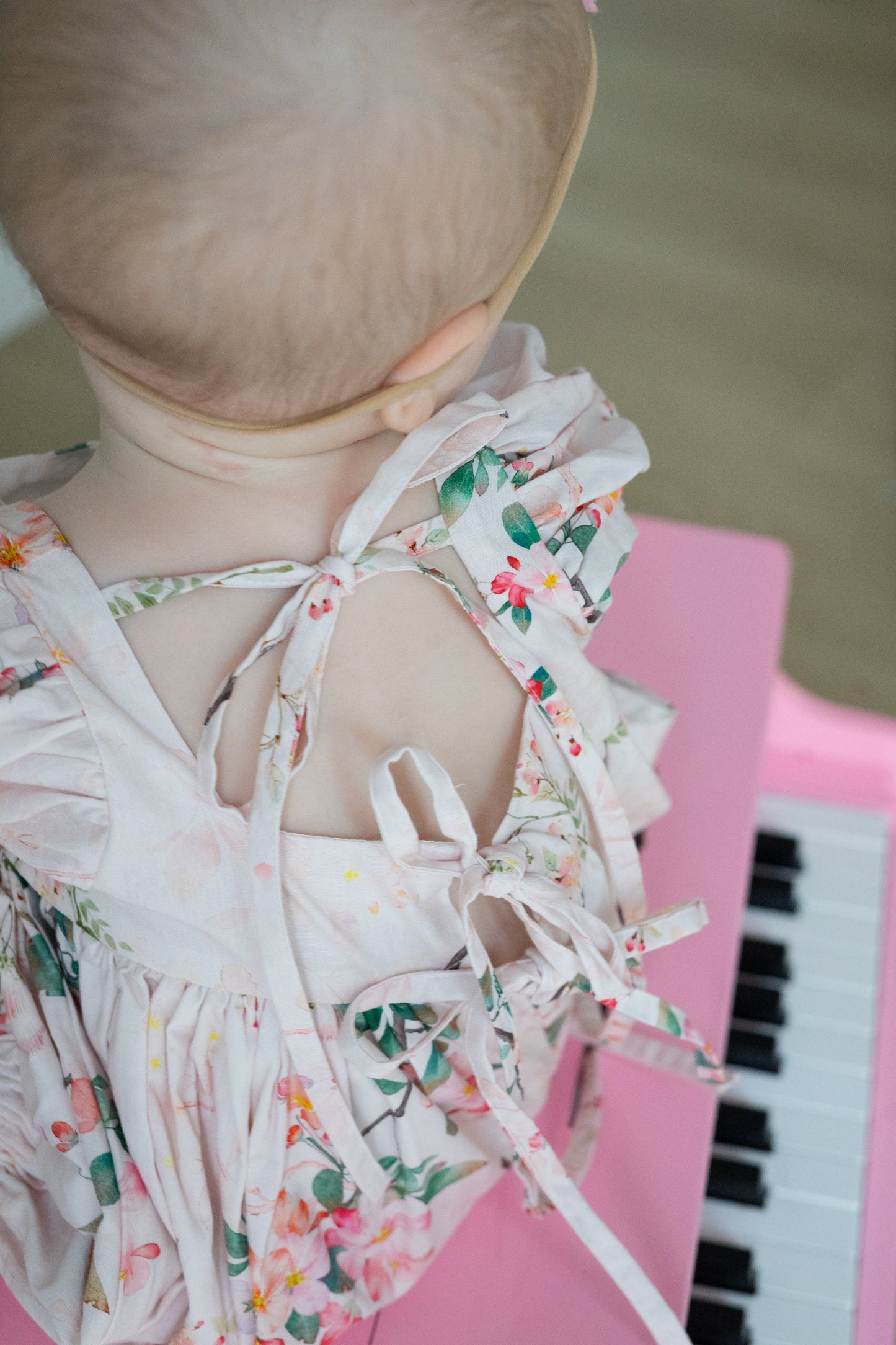 Baby in a floral Bubble  sitting on a pink piano