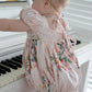 Baby in a floral bubble standing in front of a piano