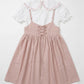 Pink dress with lace-up front and white ruffled top on a light gray background