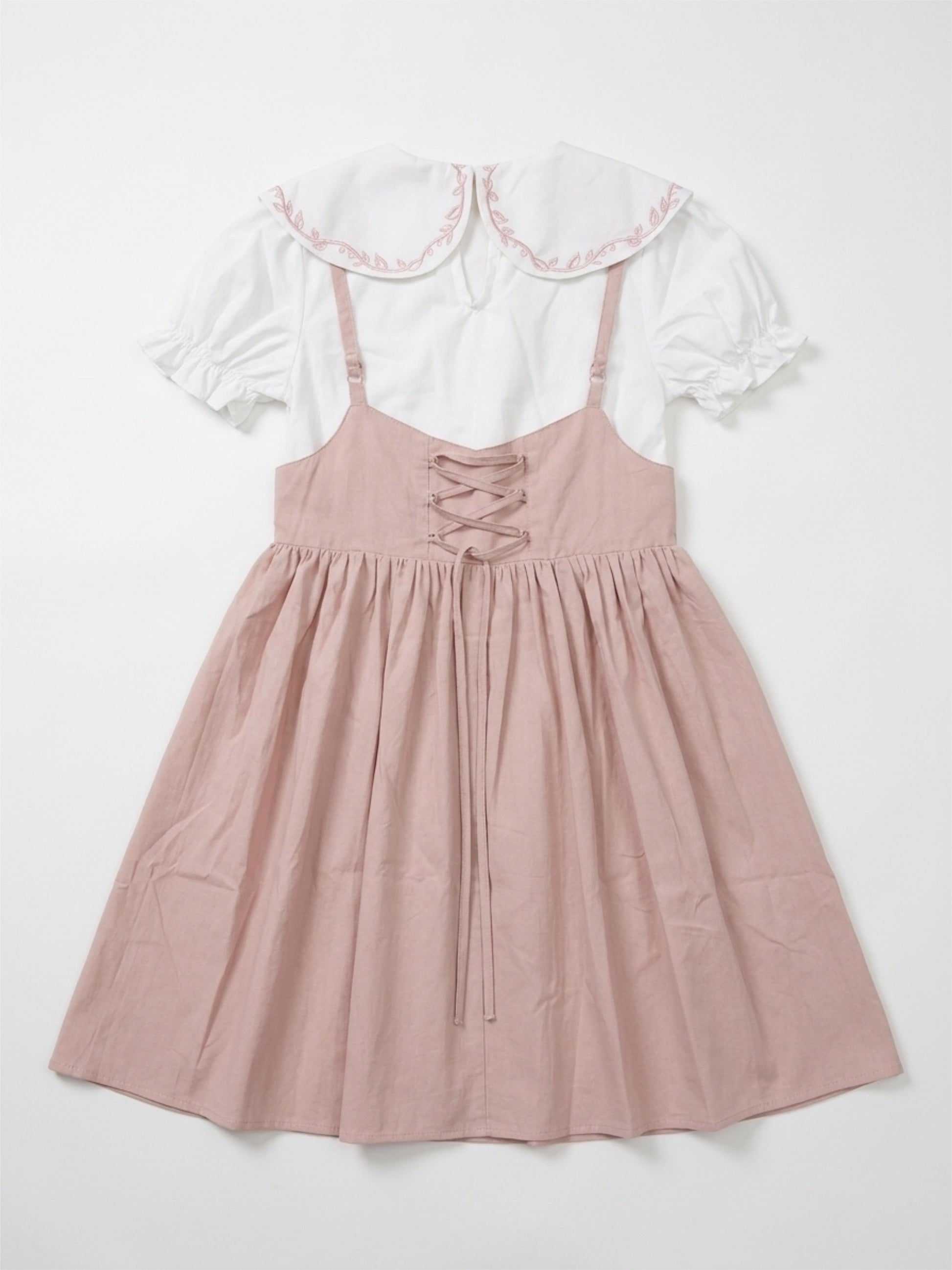 Pink dress with lace-up front and white ruffled top on a light gray background