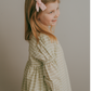 A child wearing a blush vine stripe dress with soft shirred sleeves and a ruffled hem.
