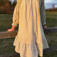 Person wearing a long, light-colored dress standing on a wooden fence in an outdoor setting.