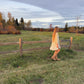 Woman walking in a field with a wooden fence and trees in the background