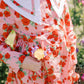 Child wearing a pink floral dress holding a colorful flower in a garden setting