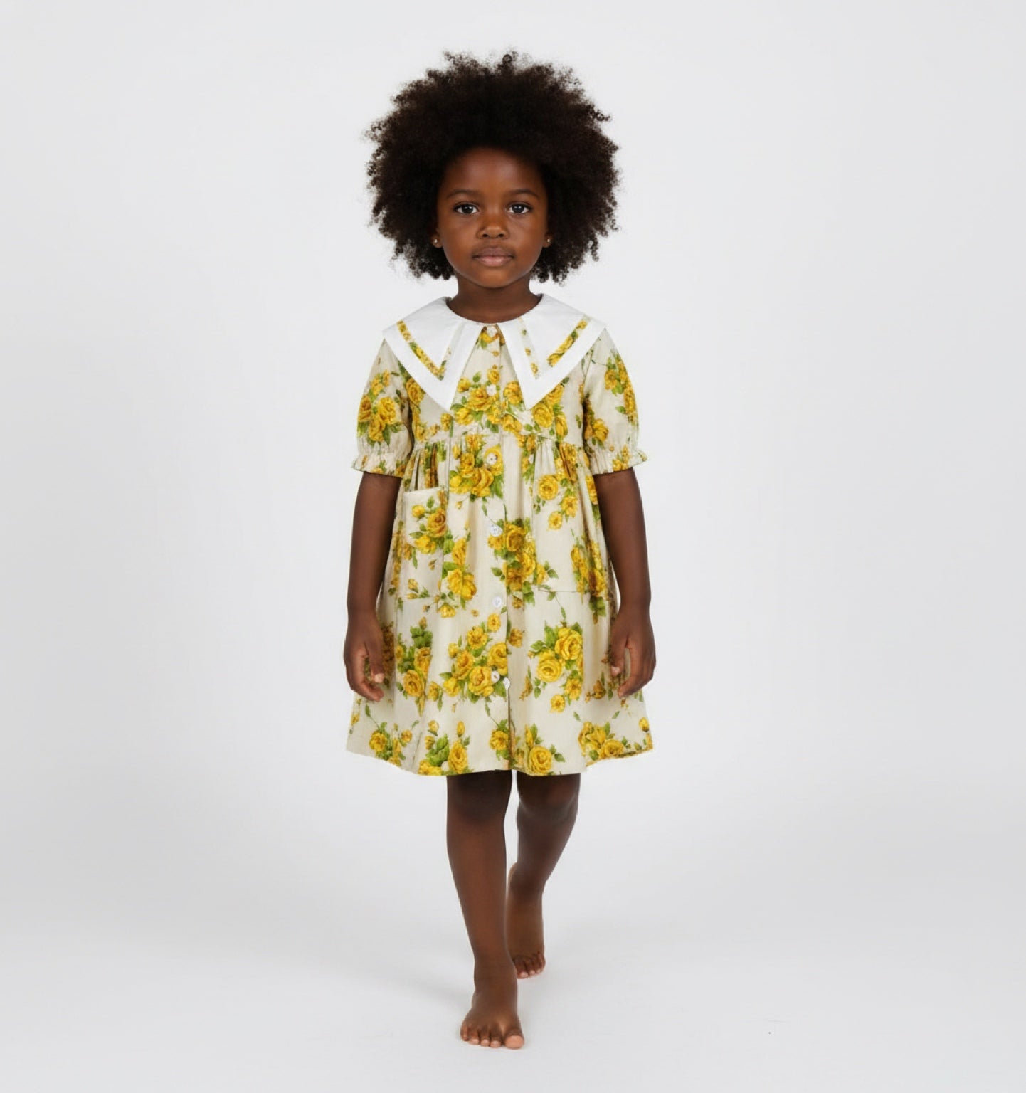 Young girl wearing a yellow floral dress on a white background