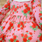 Pink dress with red floral pattern worn by a child