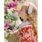 Young girl smelling a pink flower in a garden