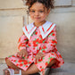 Young girl in a floral dress sitting on steps.