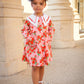 Child wearing a floral dress standing in front of classical architecture