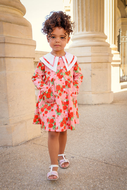 Child wearing a floral dress standing in front of classical architecture