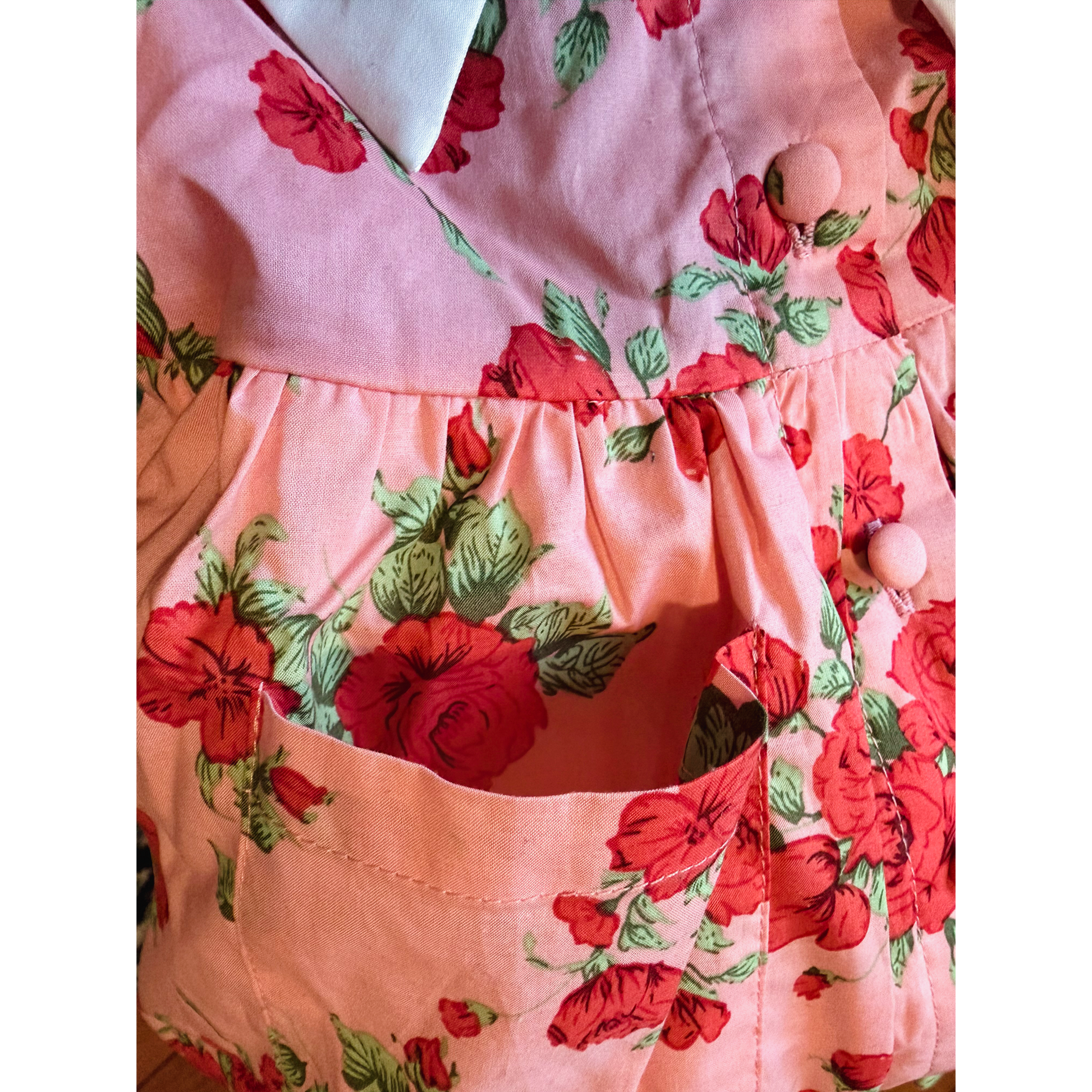 Floral dress with red flowers and green leaves on a pink background