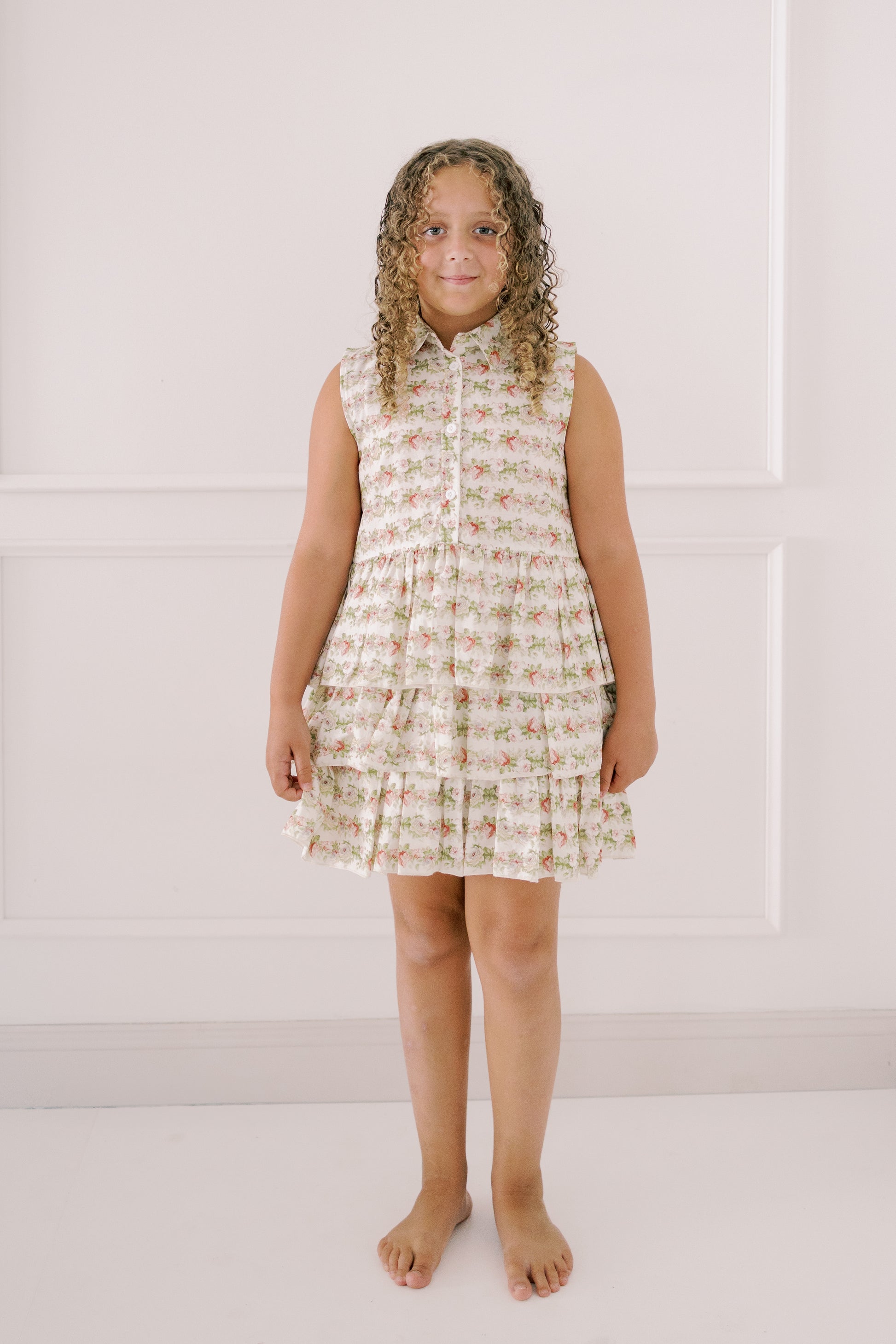 Young girl wearing a sleeveless floral dress against a white background