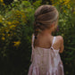 Image of girl wearing a pink dress with adjustable straps and wooden buttons down the back