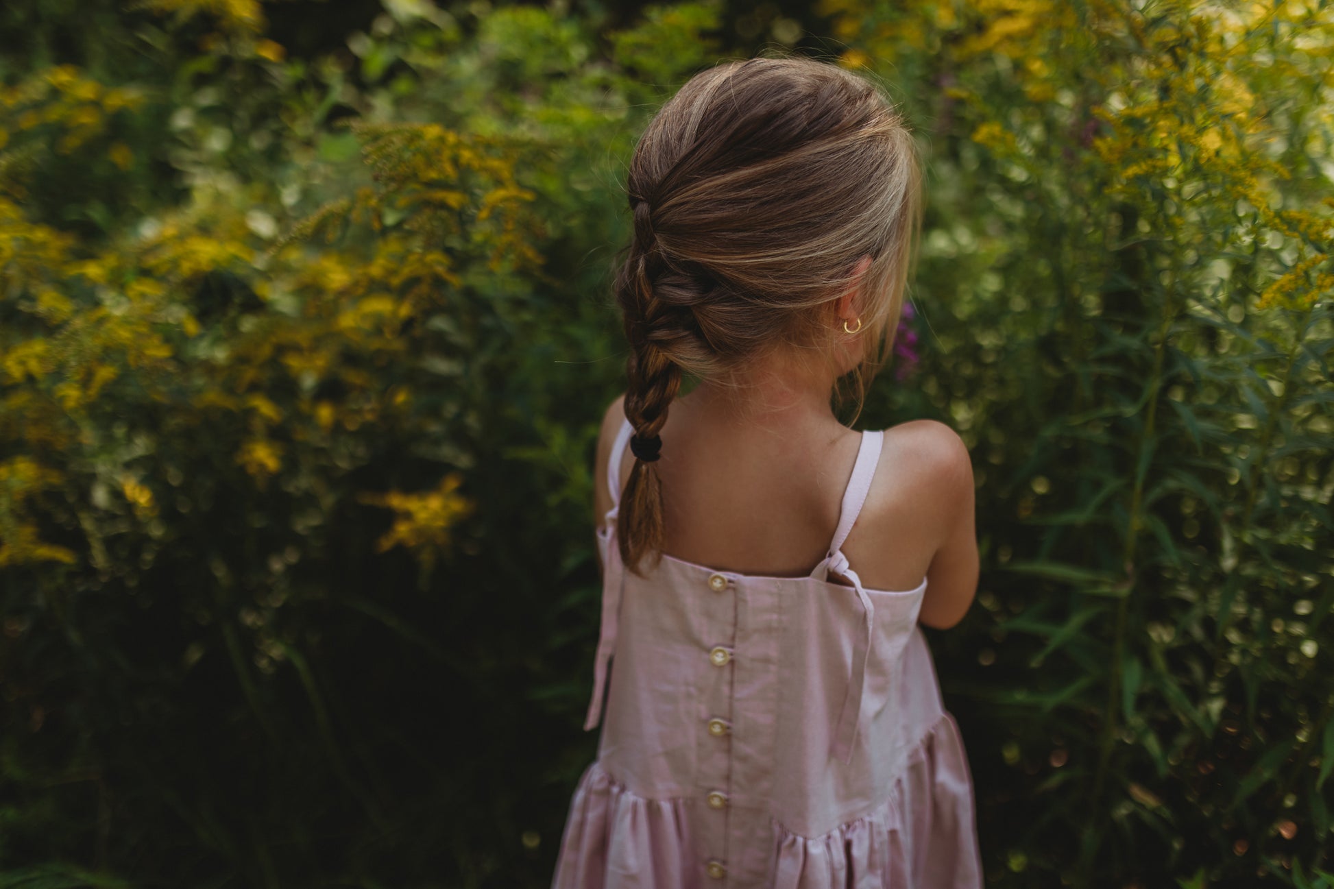 Image of girl wearing a pink dress with adjustable straps and wooden buttons down the back