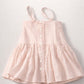 Pink dress with button details on a light gray background