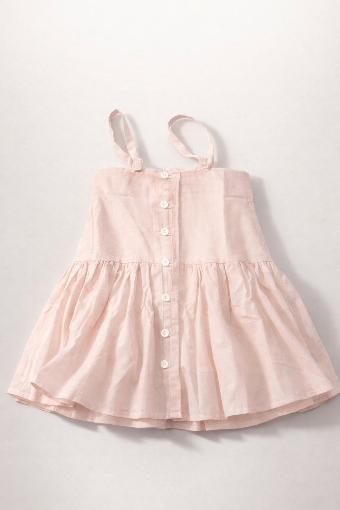 Pink dress with button details on a light gray background
