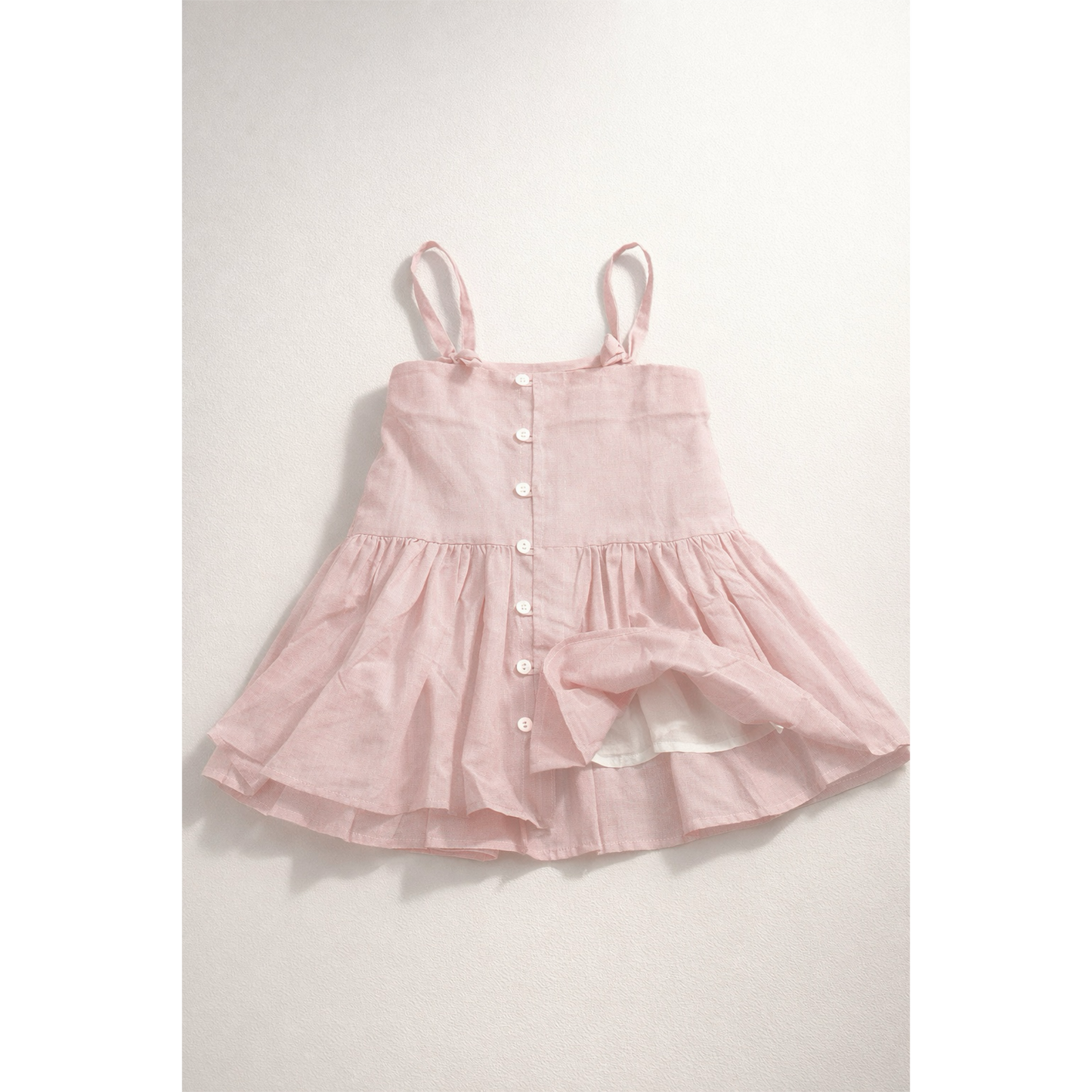 Pink dress with button details on a light gray background
