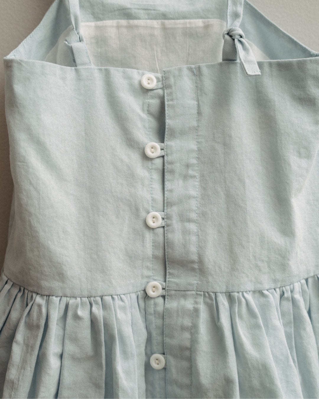 Light blue dress with buttons on a plain background