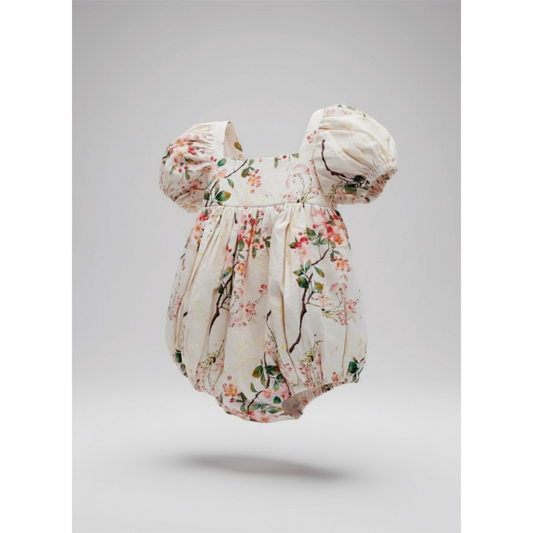 Floral baby romper with matching headband on a gray background