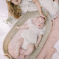 Two children in matching outfits lying on a blanket with a baby in a Moses basket.